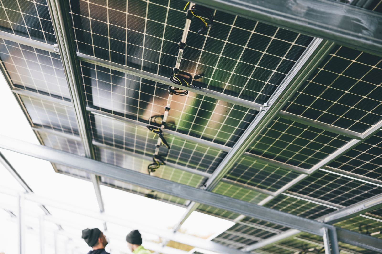 A close view of solar panels being installed, with technicians working behind them.
