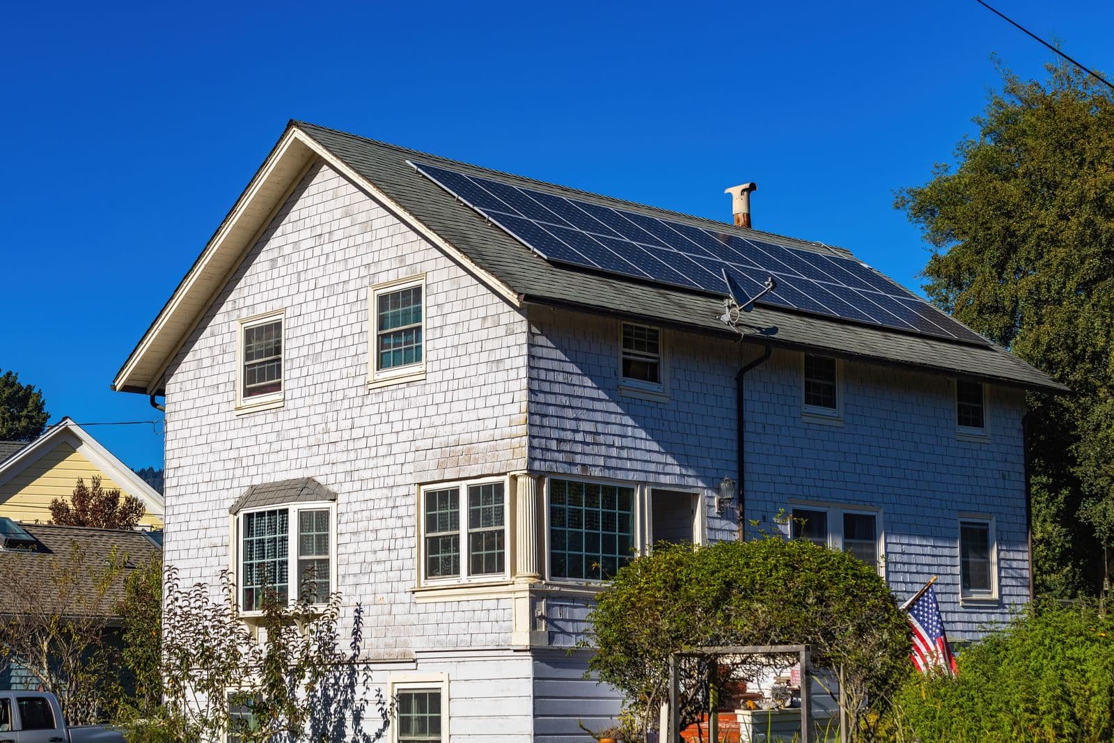 A two storey white house with solar panels across its roof.