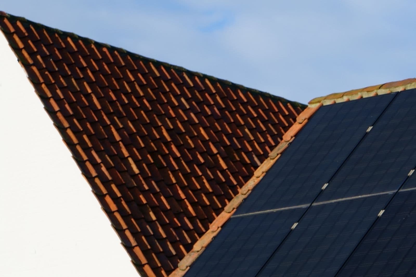 Solar panels mounted on a tiled roof, with the tile line visible alongside them.