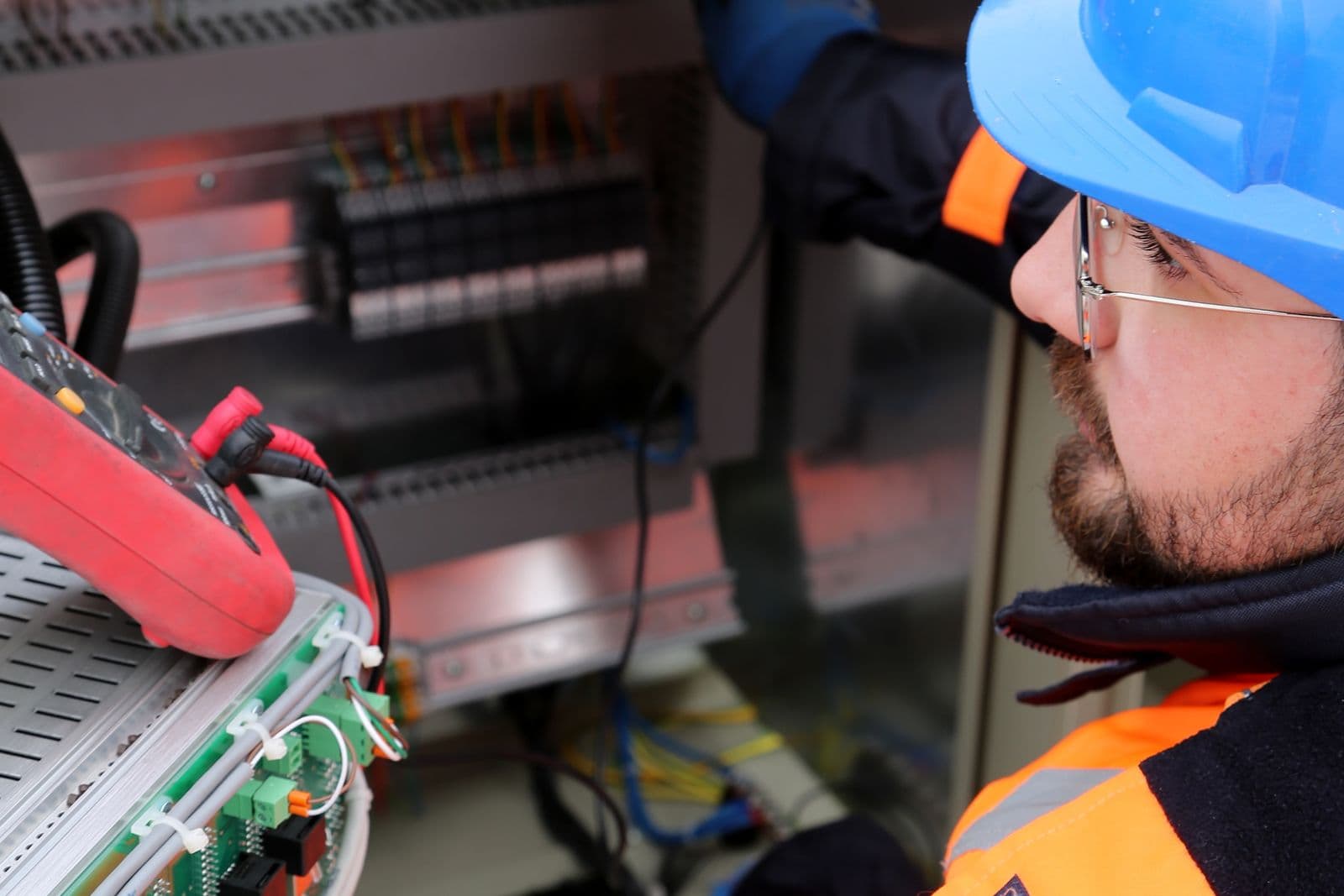An electrician in a hard hat working at a switchboard.