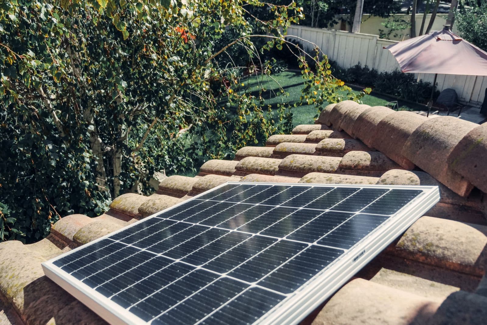 A close view of a solar panel installed on a tiled house roof in bright sun.