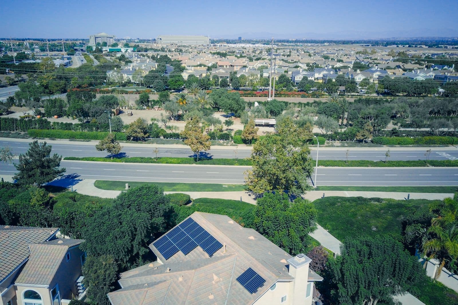 An aerial view of a suburban street where several houses carry rooftop solar.