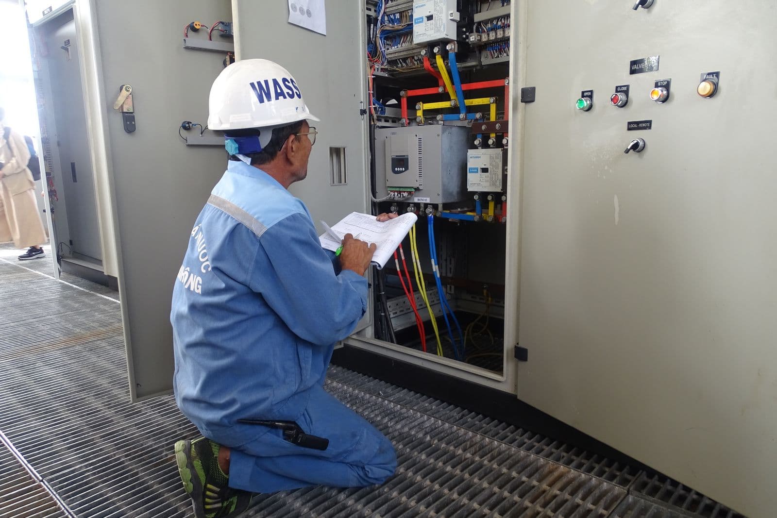 An engineer inspecting an electrical control panel.