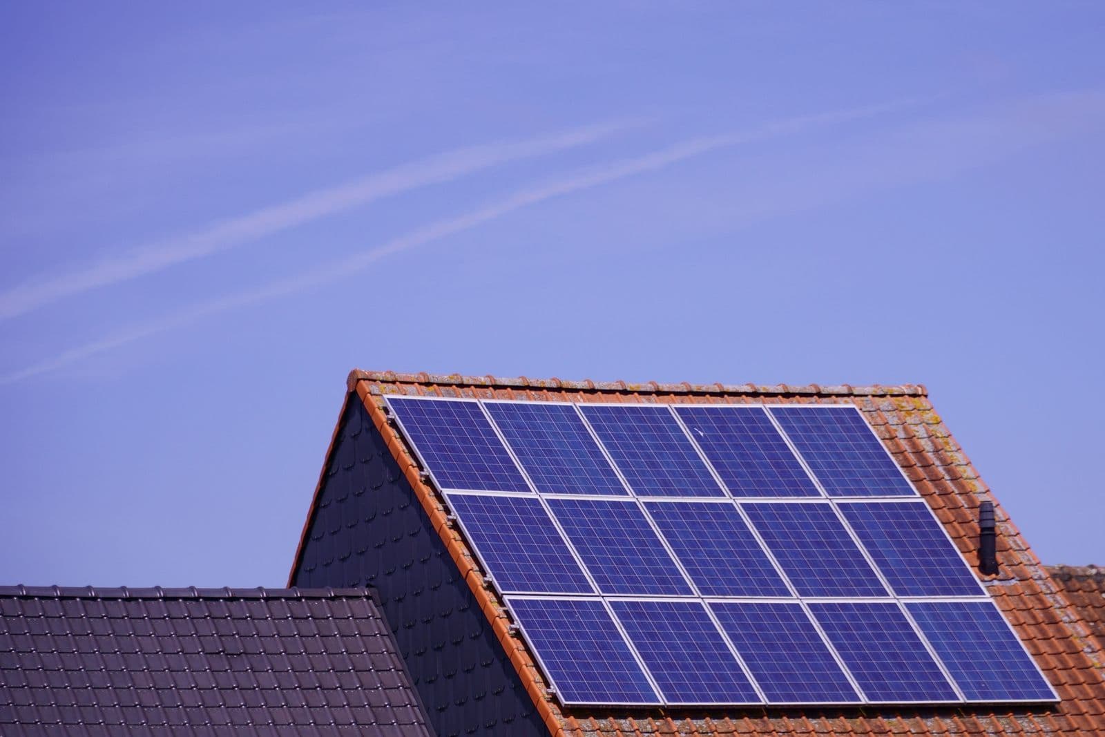 Solar panels on a tiled rooftop under a clear sky.