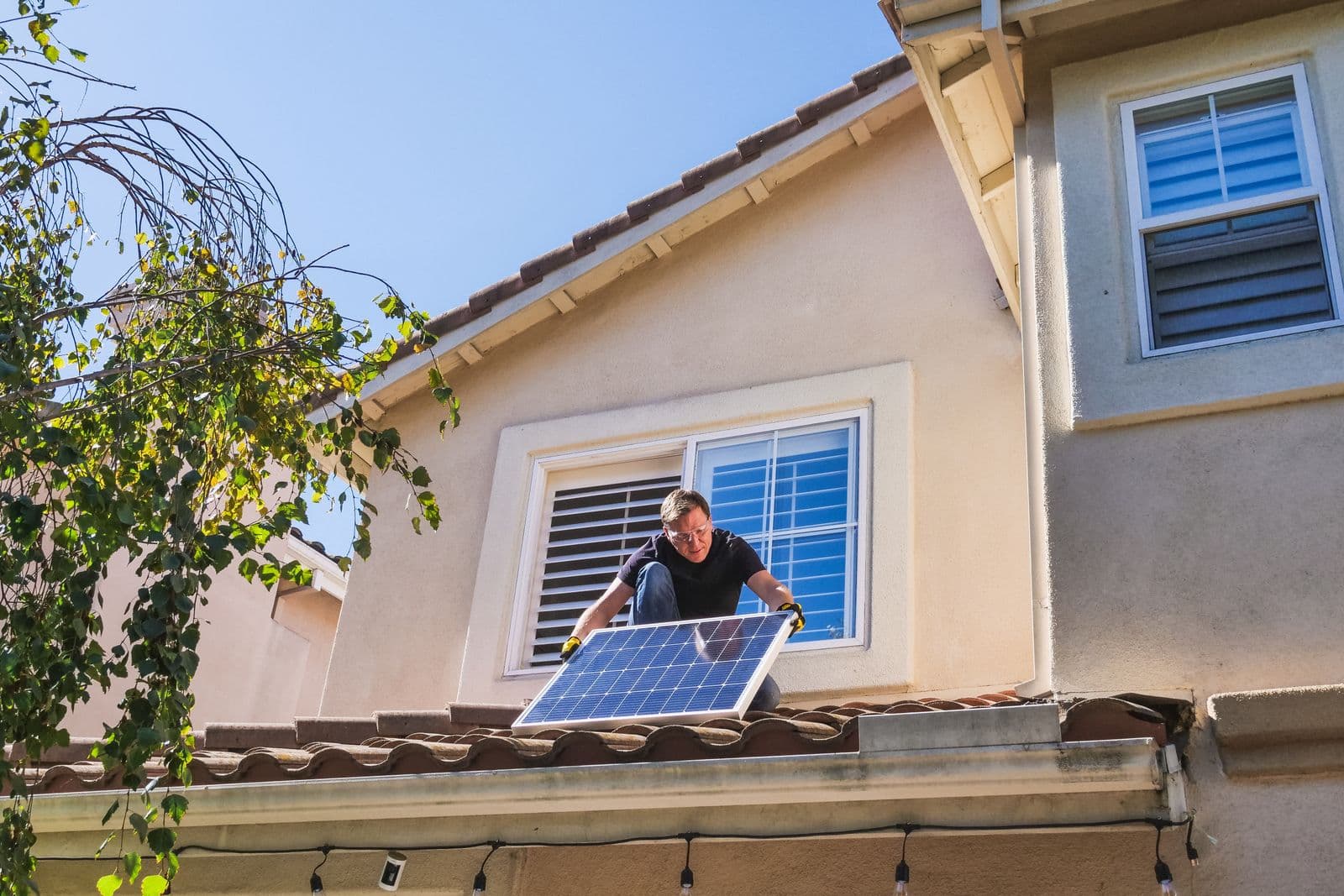 A technician inspecting a photovoltaic panel on a house roof.