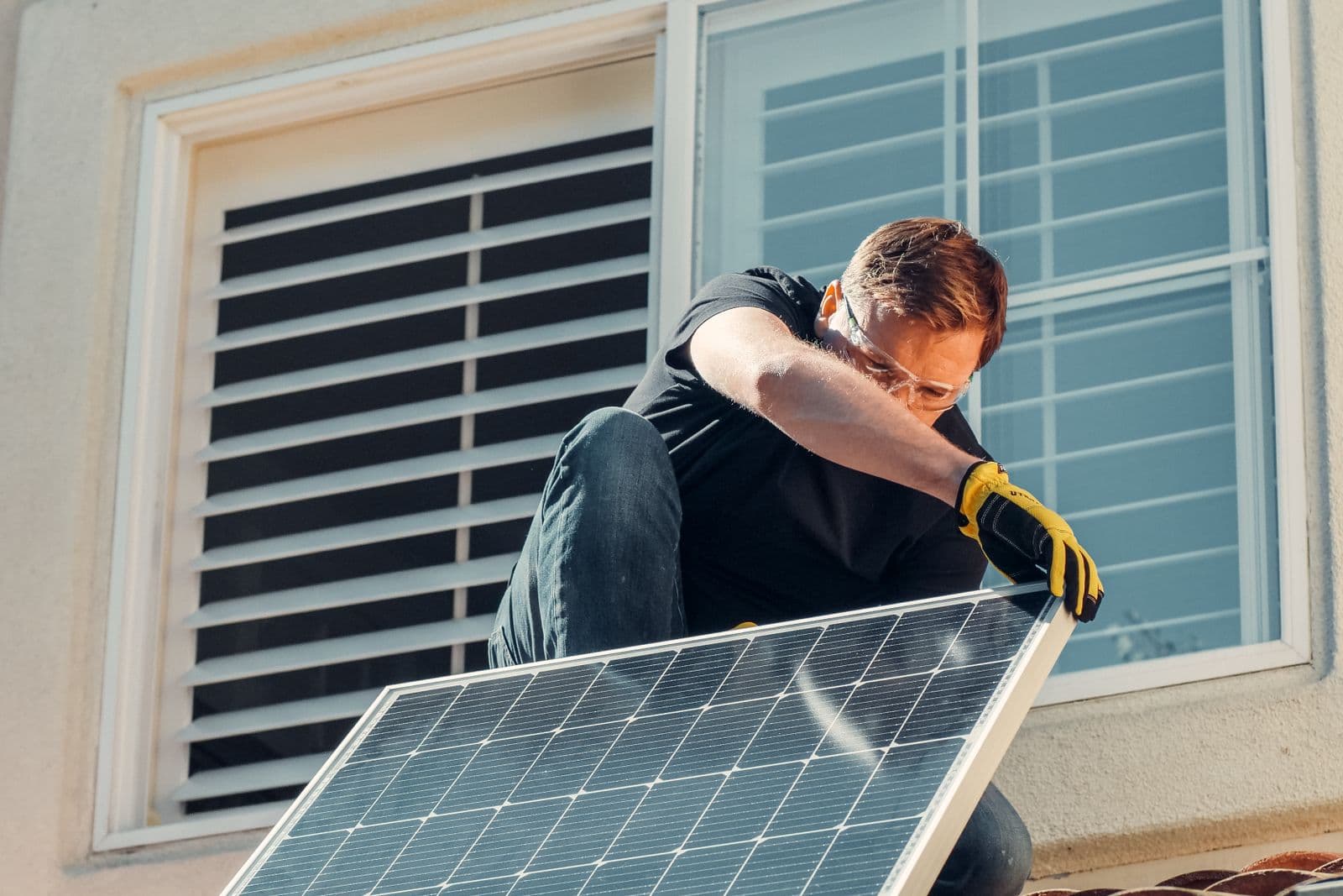 A worker fitting a solar panel on a residential roof.