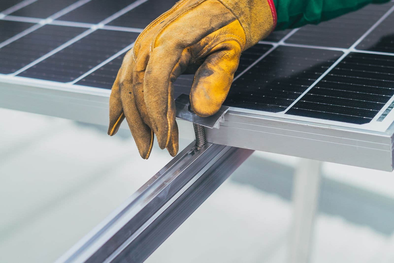A gloved hand resting on the surface of a solar panel during installation.