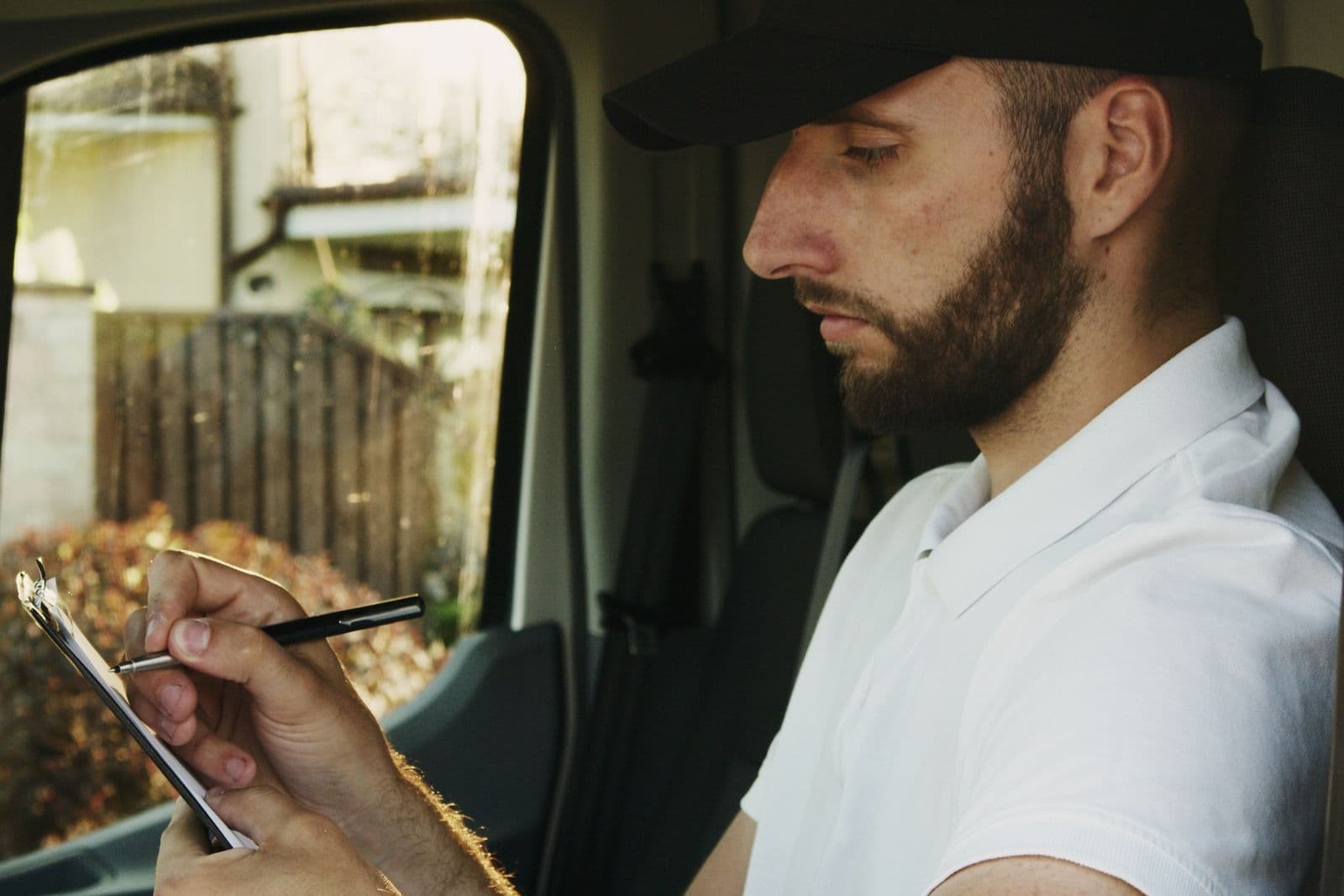 A tradesperson filling in a clipboard while sitting in a work van.