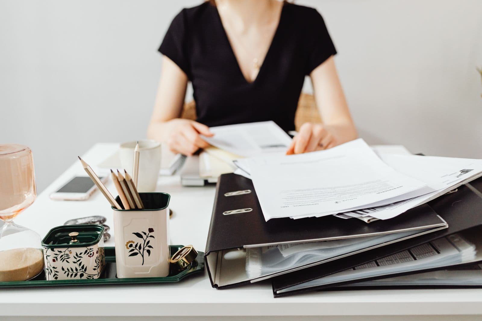 A person working through binders and job files at a desk.