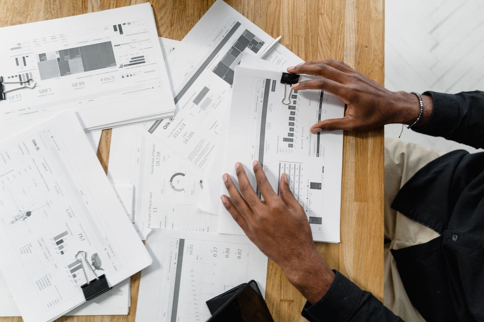 Someone reviewing financial paperwork at a wooden table.